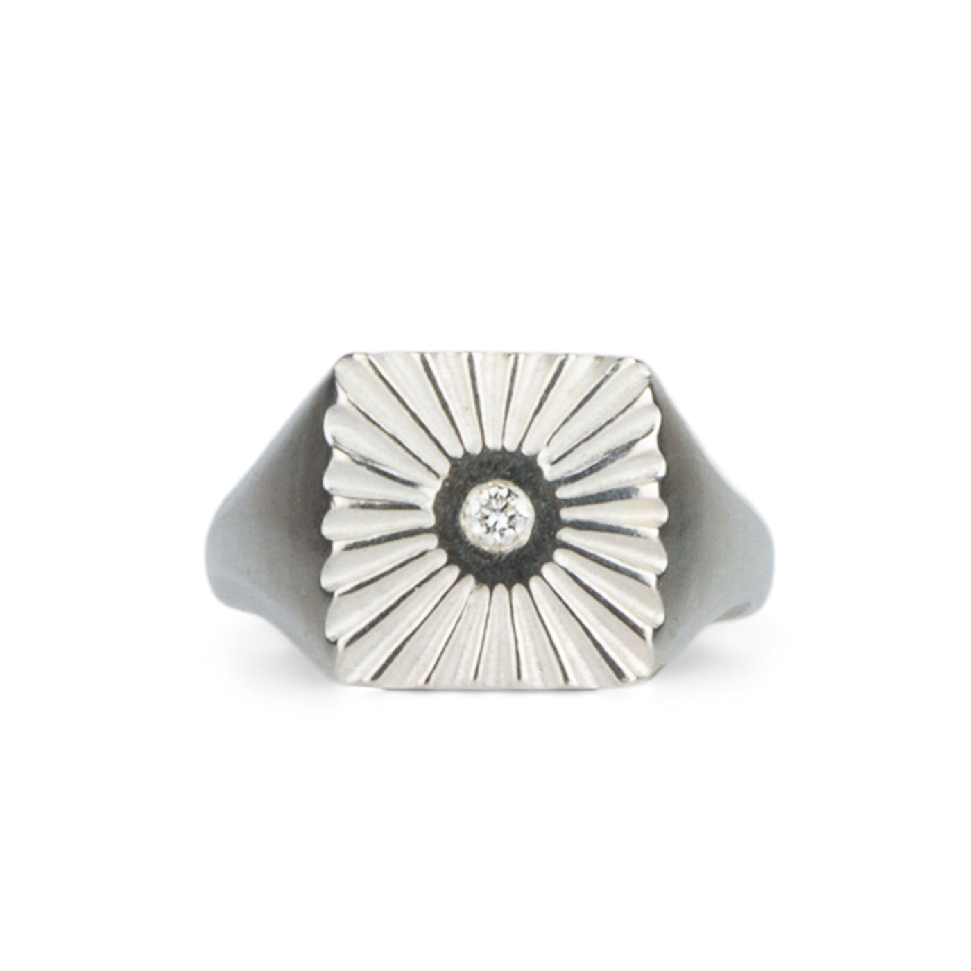 Large silver square signet ring with a carved sunburst pattern and diamond center on a white background