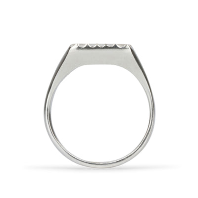 Profile view of Large silver square signet ring with a carved sunburst pattern and diamond center on a white background