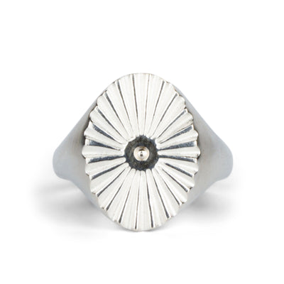 Large silver oval signet ring with a carved sunburst pattern and a silver bead center on a white background