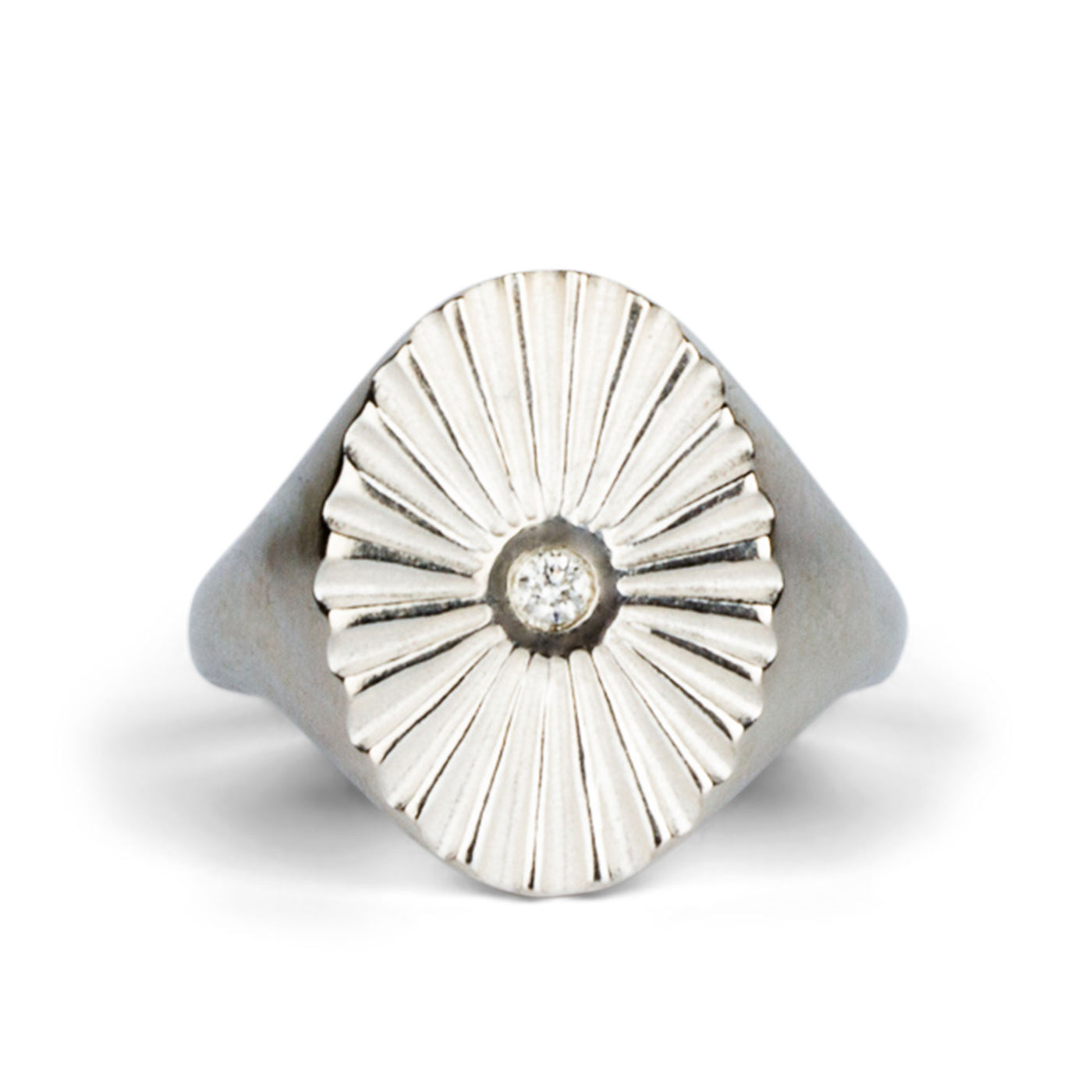 Large silver oval signet ring with a carved sunburst pattern and diamond center on a white background