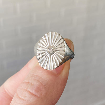 silver oval sunburst signet ring with a diamond center