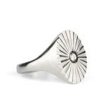Alternate side view of Large silver oval signet ring with a carved sunburst pattern and diamond center on a white background