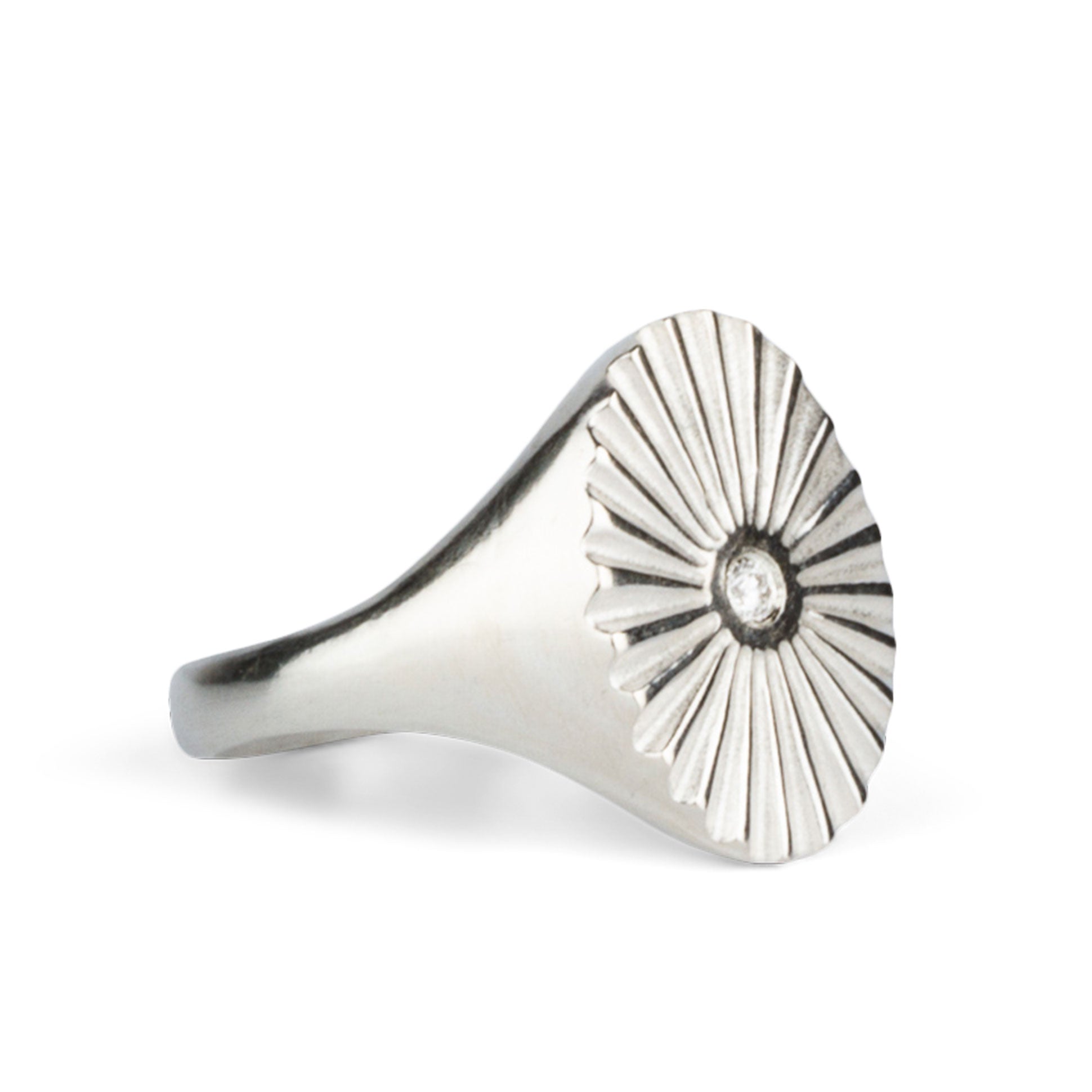 Alternate side view of Large silver oval signet ring with a carved sunburst pattern and diamond center on a white background