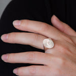 Large silver oval signet ring with a carved sunburst pattern and diamond center on a hand