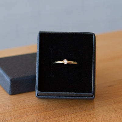 14k yellow gold small aurora stacking ring with a 1.5mm center diamond and engraved border in a gift box