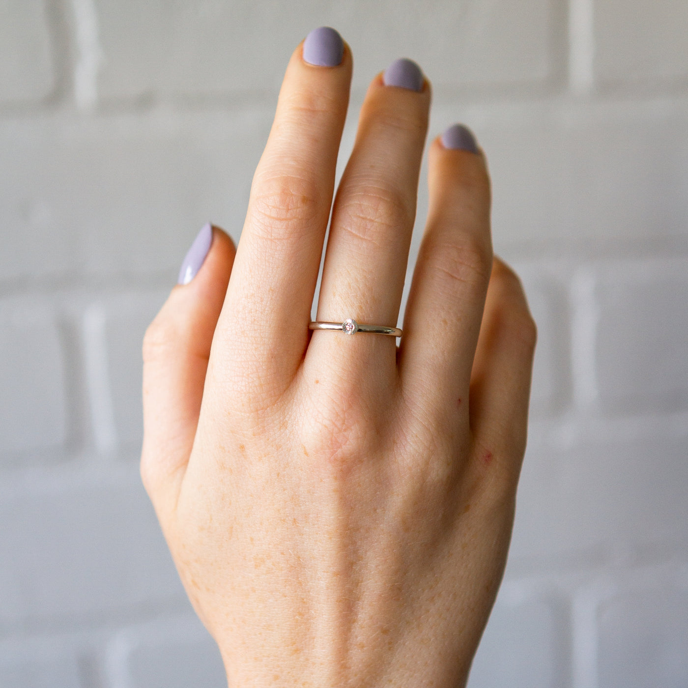 sterling silver small aurora stacking ring with a 1.5mm center diamond and engraved border on a hand