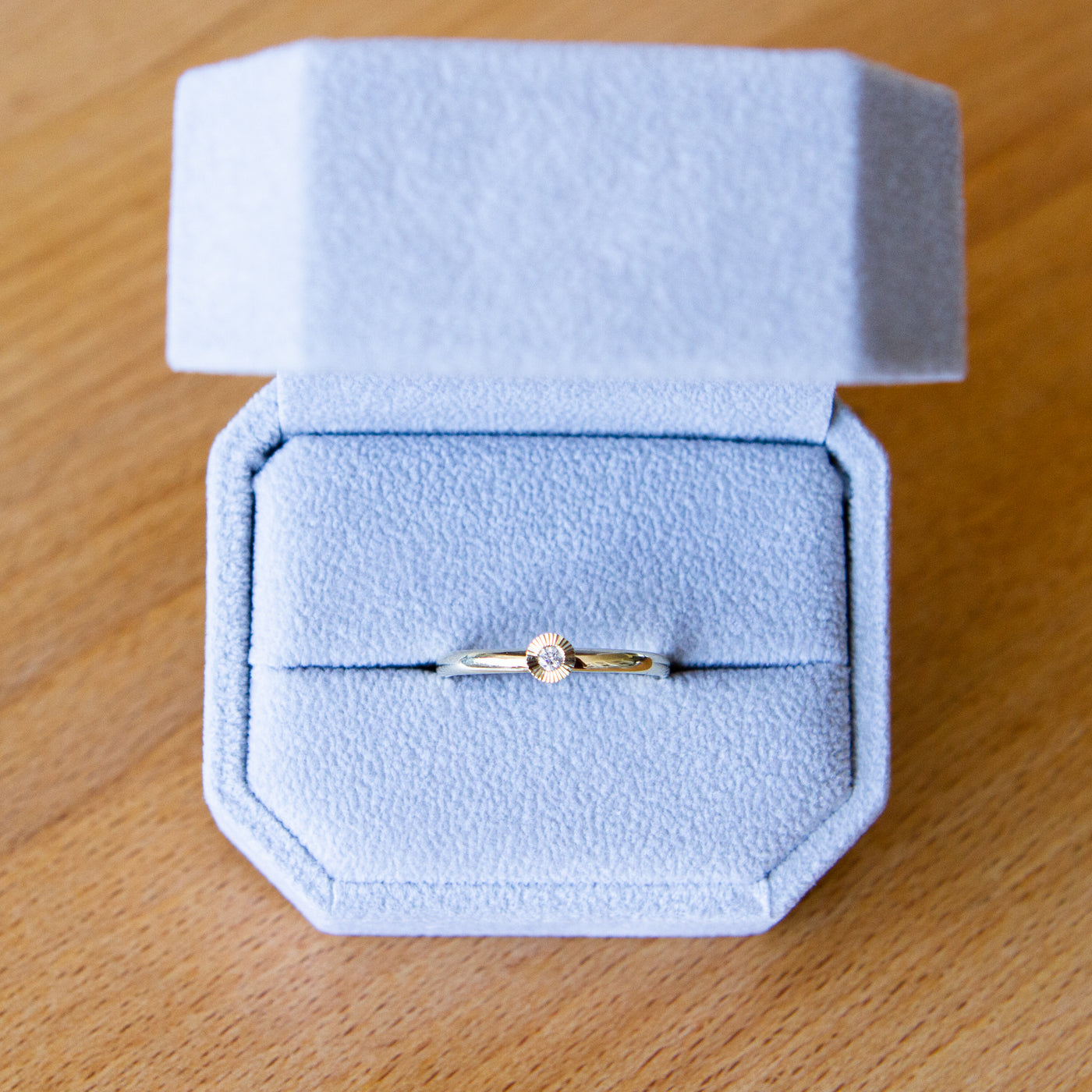 14k yellow gold small aurora stacking ring with a 2mm center diamond and engraved border in a gift box