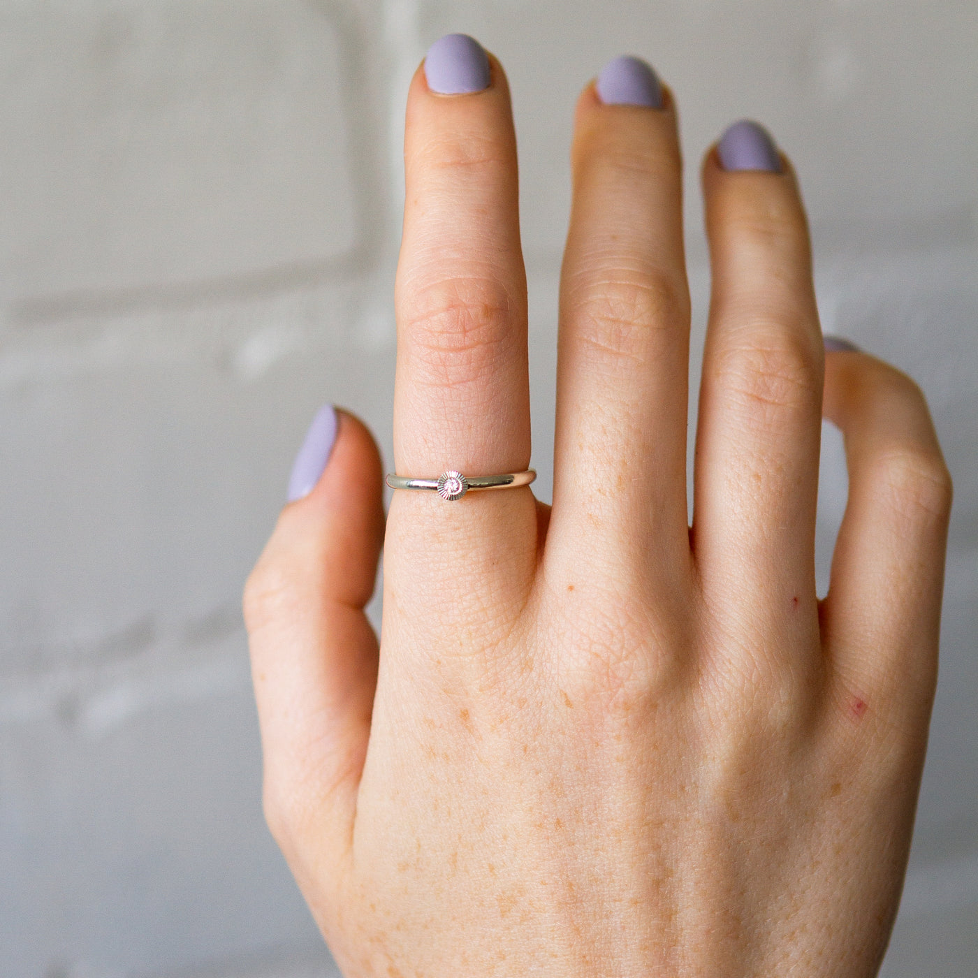 sterling silver small aurora stacking ring with a 2mm center diamond and engraved border on a hand