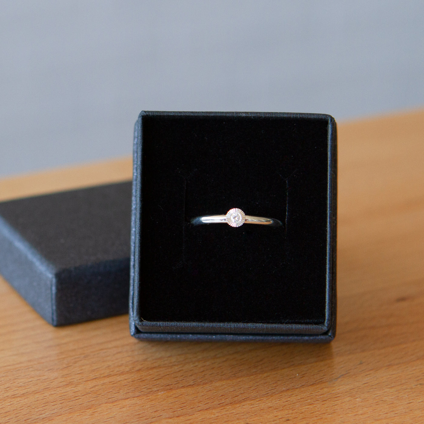 sterling silver small aurora stacking ring with a 2mm center diamond and engraved border in a gift box