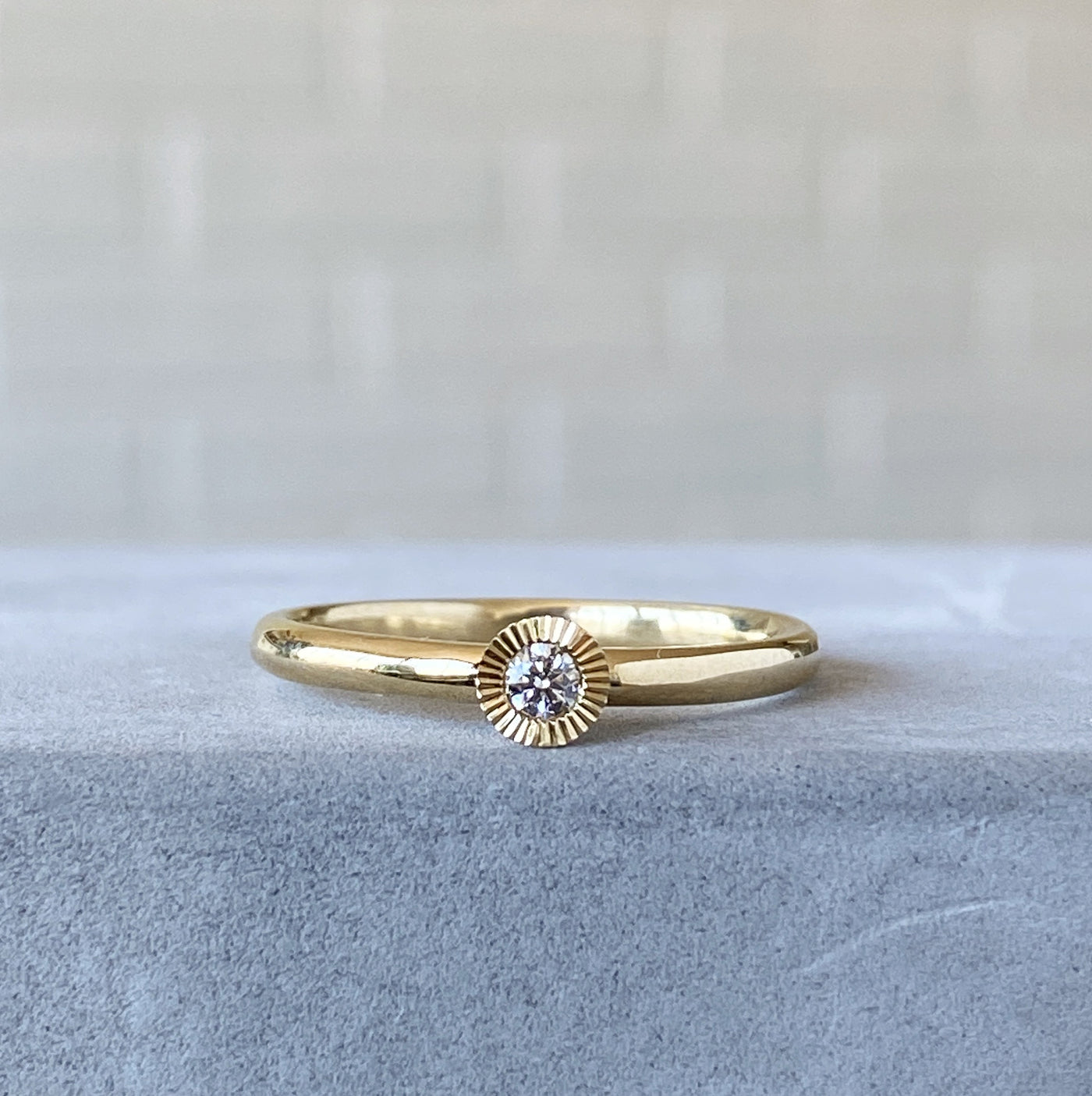 14k yellow gold medium aurora stacking ring with a 2.5mm center diamond and engraved border on a hand