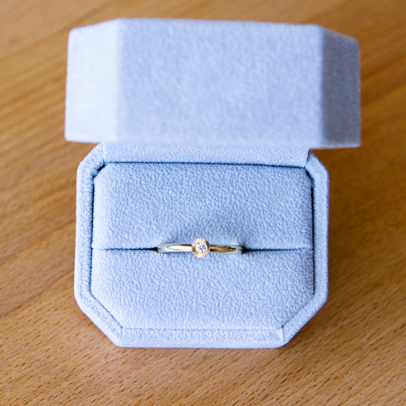 14k yellow gold medium aurora stacking ring with a 2.5mm center diamond and engraved border in a ring box