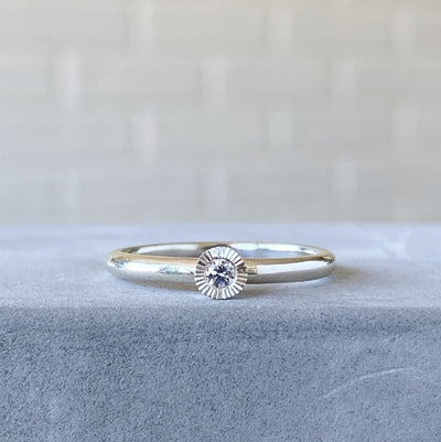 sterling silver large aurora stacking ring with a 3mm center diamond and engraved border on concrete