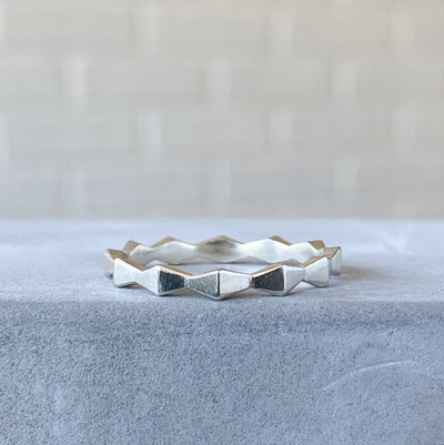 Sterling silver geometric trapezoid carved zig zag stacking band resting on concrete 2