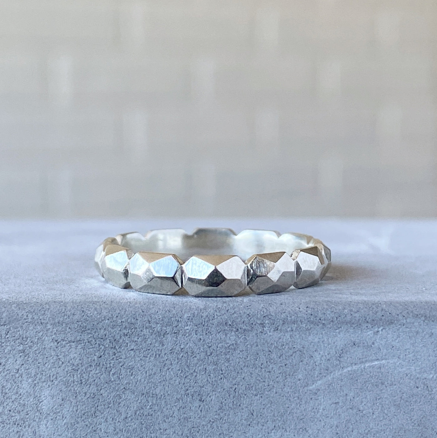 sterling silver faceted carved nugget eternity band resting on concrete