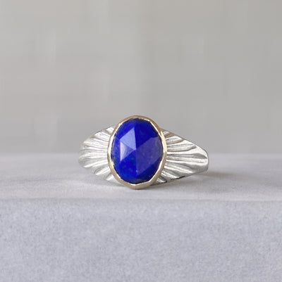 Oval Rose cut Lapis Silver and Gold Sunburst Ring sitting in front of a white wall, front angle