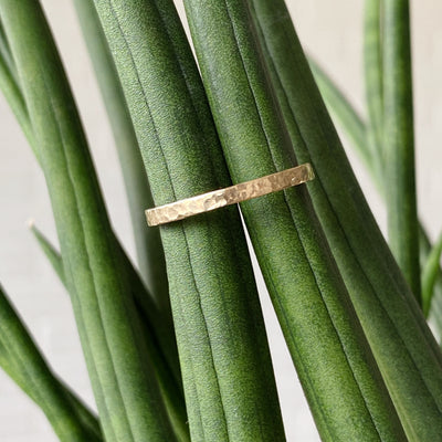 Flat hammered yellow gold wedding band in natural light