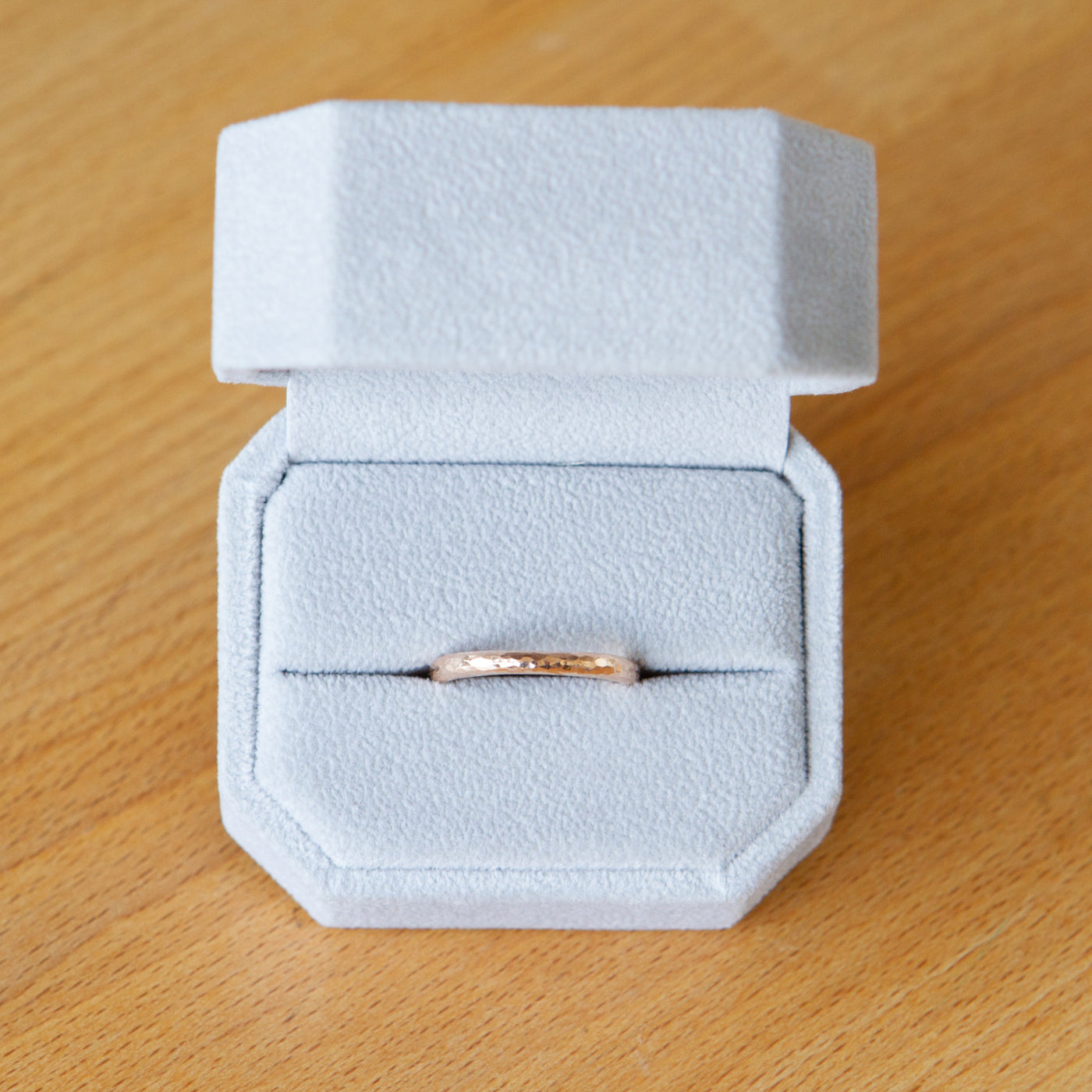 14k rose gold blue ridge half round hammered band in a ring box by Corey Egan