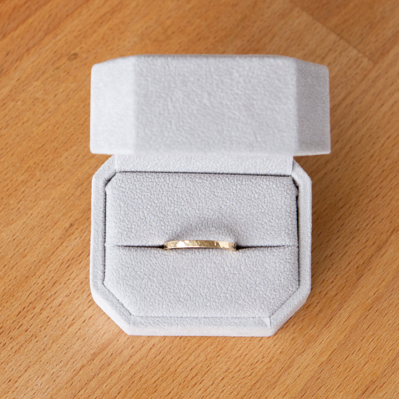 Flat hammered yellow gold wedding band in a ring box
