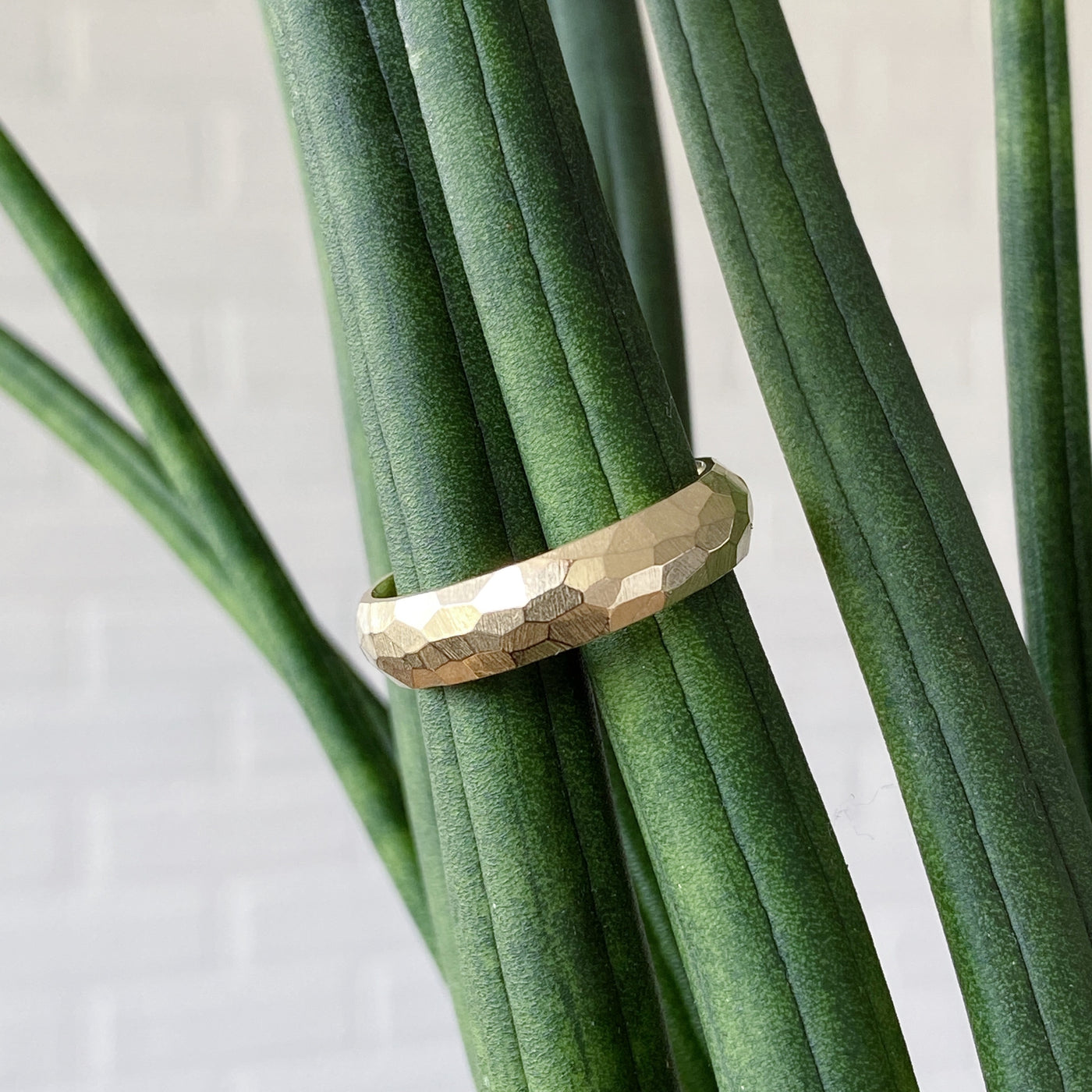 Wide faceted yellow gold wedding band in natural light