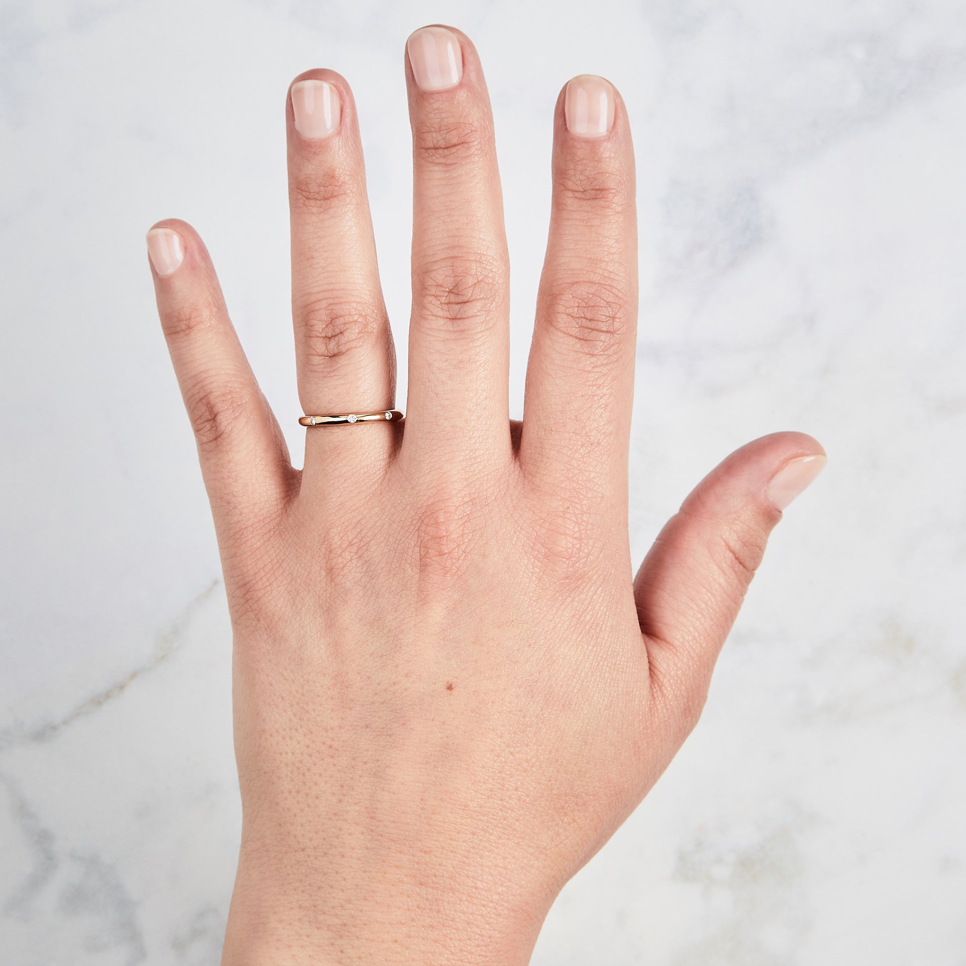 Yellow gold Lassen Diamond Band with flush set equidistant diamonds on a hand by Corey Egan