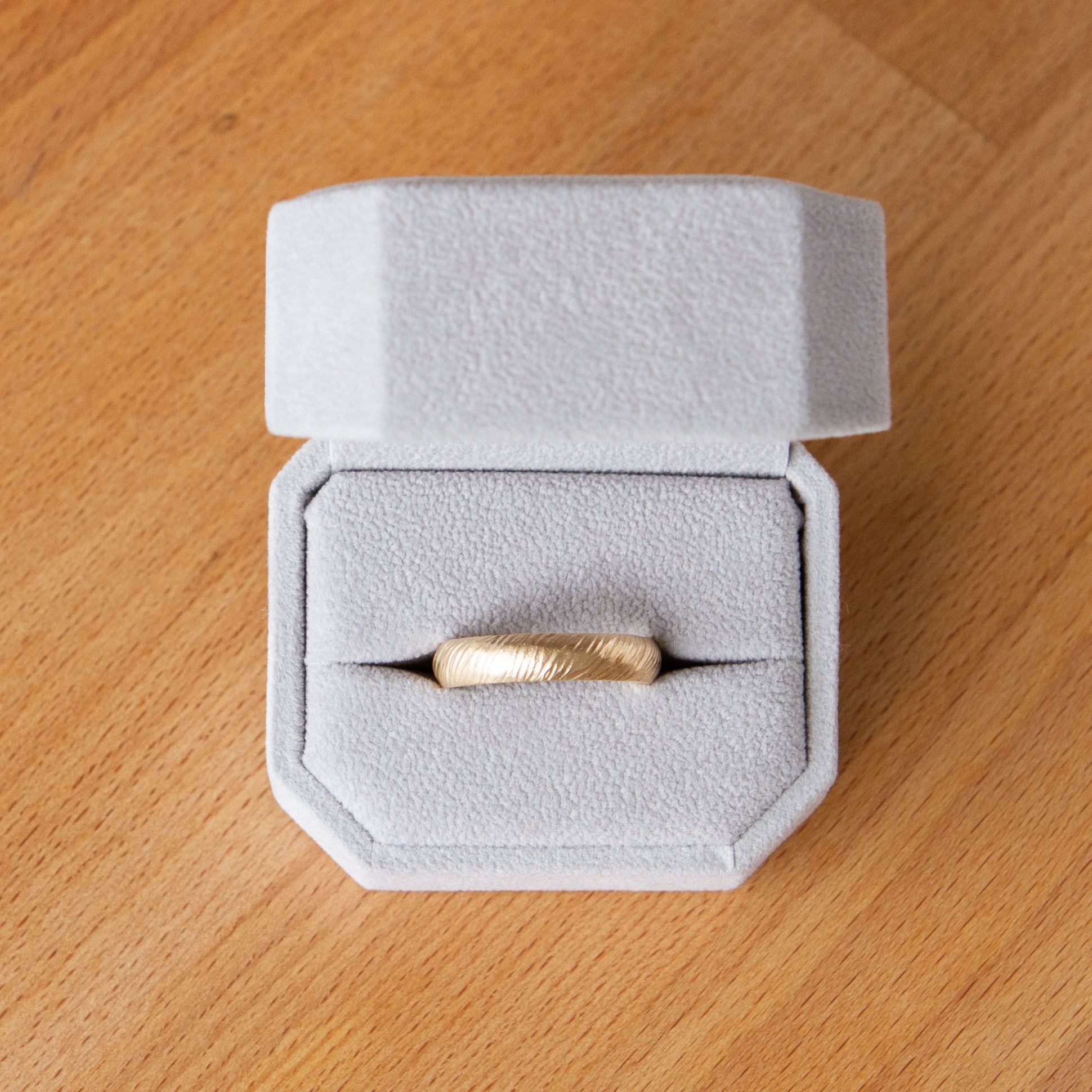 Mackinac half round 14k yellow gold carved sandy surface wedding band in a ring box