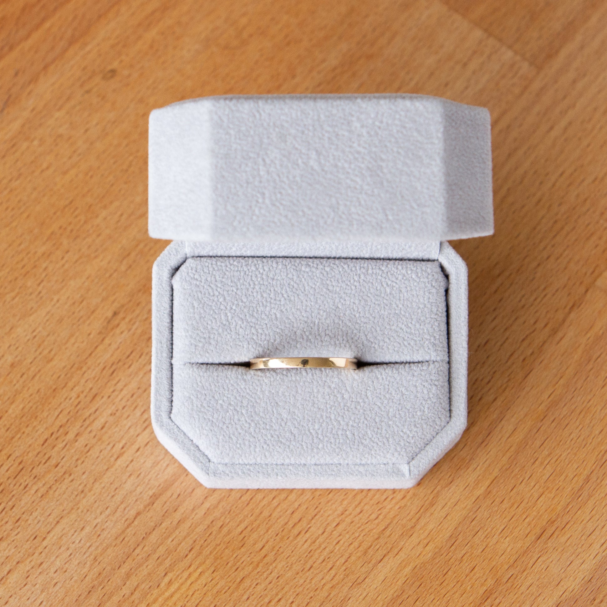 Shiny muir flat thin yellow gold wedding band in a ring box