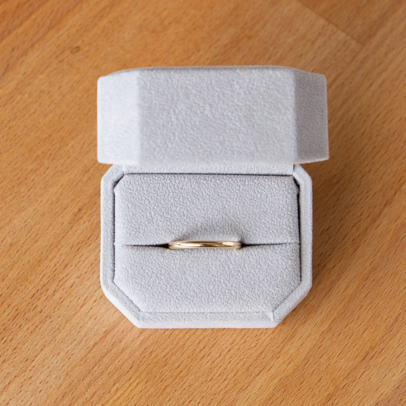 Shiny half-round thin Muir wedding band in 14k yellow gold in a ring box