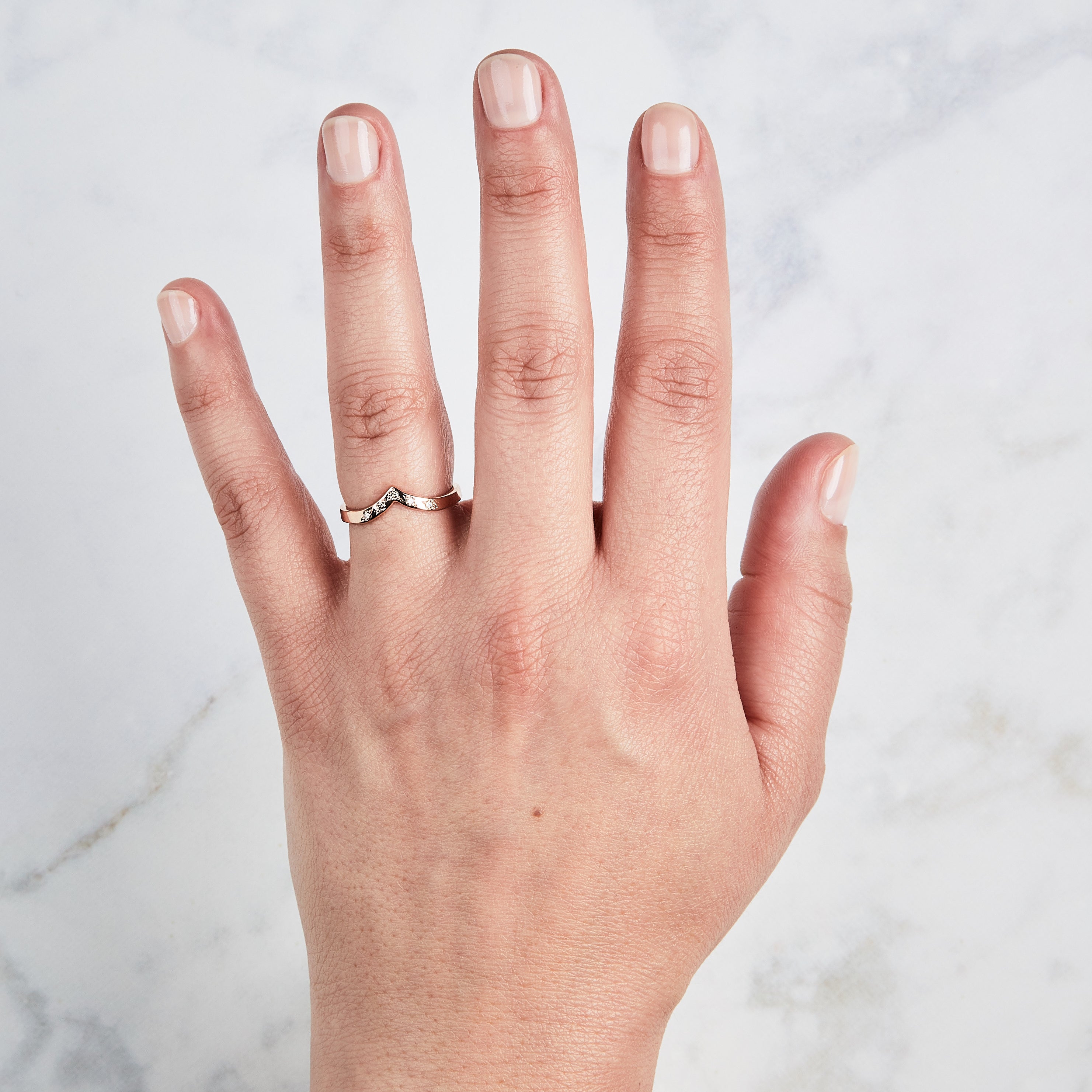 Peaked 14k rose gold band with five champagne diamonds in delicate star settings on a hand