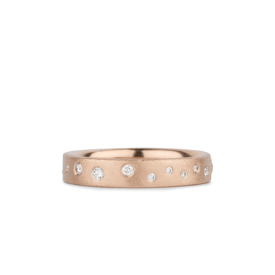 Rose gold matte texture wide wedding band with scattered flush set diamonds by Corey Egan on a white background