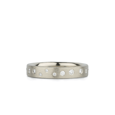 White gold matte texture wide wedding band with scattered flush set diamonds by Corey Egan on a white background