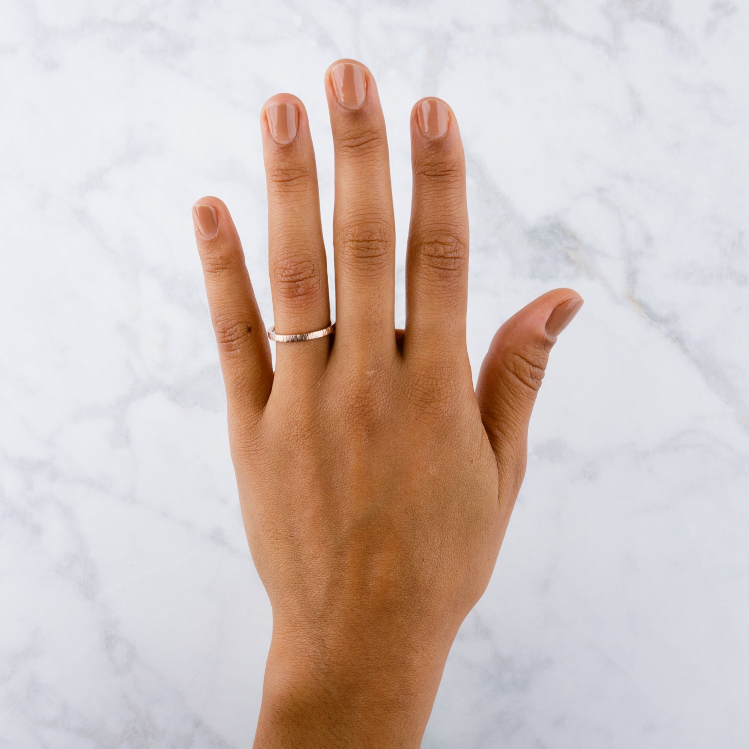 14k rose gold vertical hammered flat Zion Band on a hand by Corey Egan