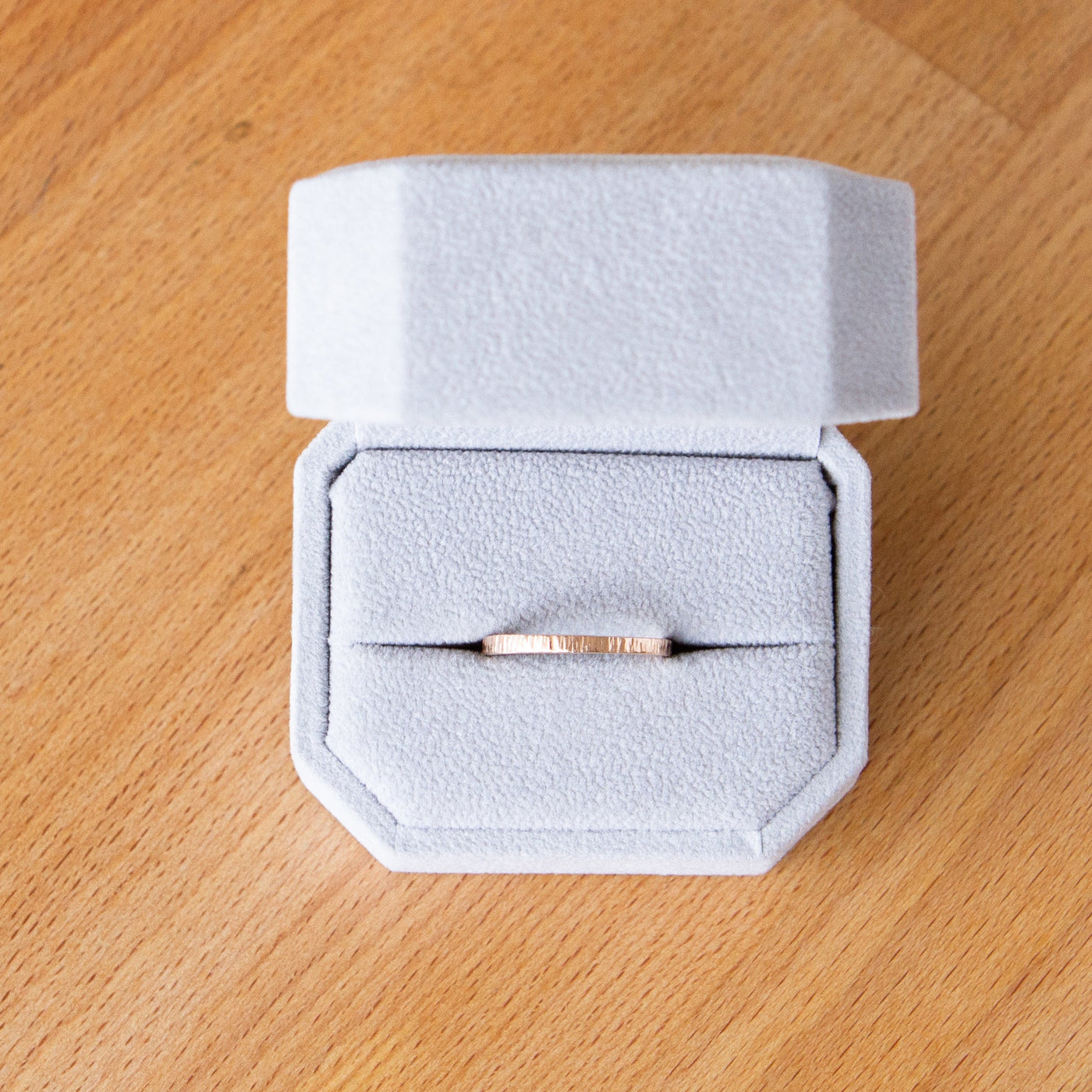 14k rose gold Thin zion flat vertical hammered wedding band in a ring box