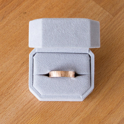 14k rose gold Zion flat wide vertical hammered wedding band in a ring box