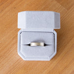 14k white gold Zion flat wide vertical hammered wedding band in a ring box