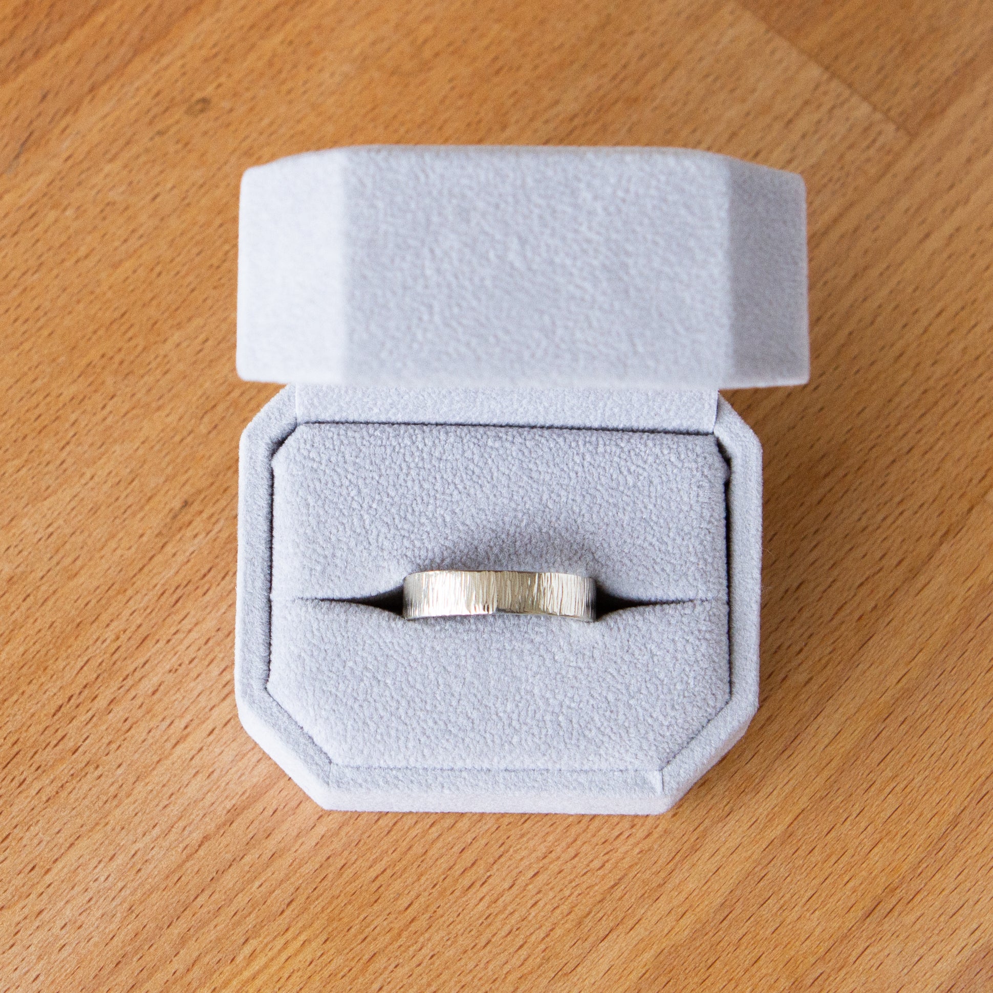 14k white gold Zion flat wide vertical hammered wedding band in a ring box