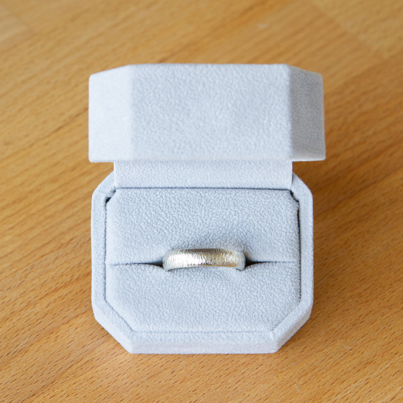14k white gold half round Zion band in a ring box by Corey Egan
