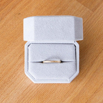 Thin Zion half round yellow gold vertical hammered wedding band in a ring box
