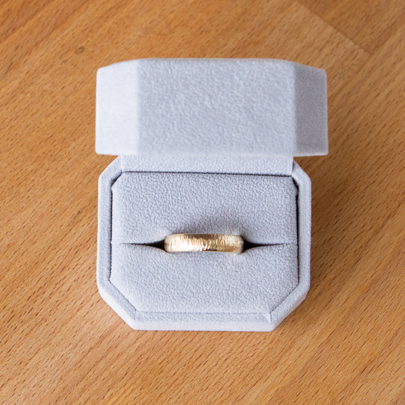 Wide Zion half round yellow gold vertical hammered wedding band in a ring box