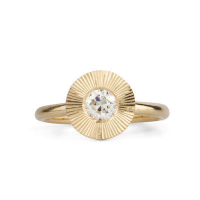 Round antique old European diamond in a 14k yellow gold Aurora ring with an engraved halo border on a white background
