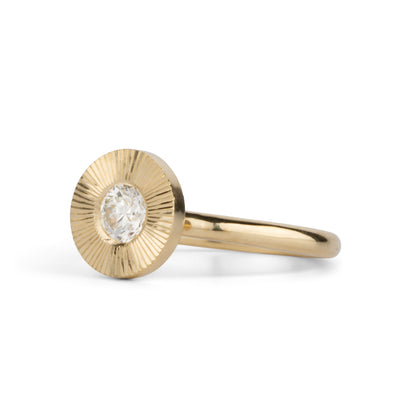 Round antique old European diamond in a 14k yellow gold Aurora ring with an engraved halo border side view on a white background