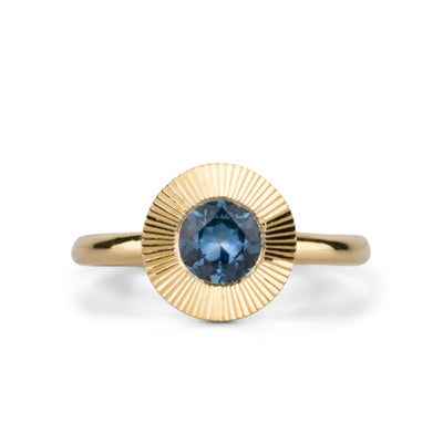 Round Medium Blue Montana sapphire in a 14k yellow gold Aurora ring with an engraved halo border. 