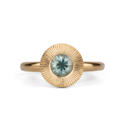 Round mint green Montana sapphire in a 14k yellow gold Aurora ring with an engraved halo border on a white background
