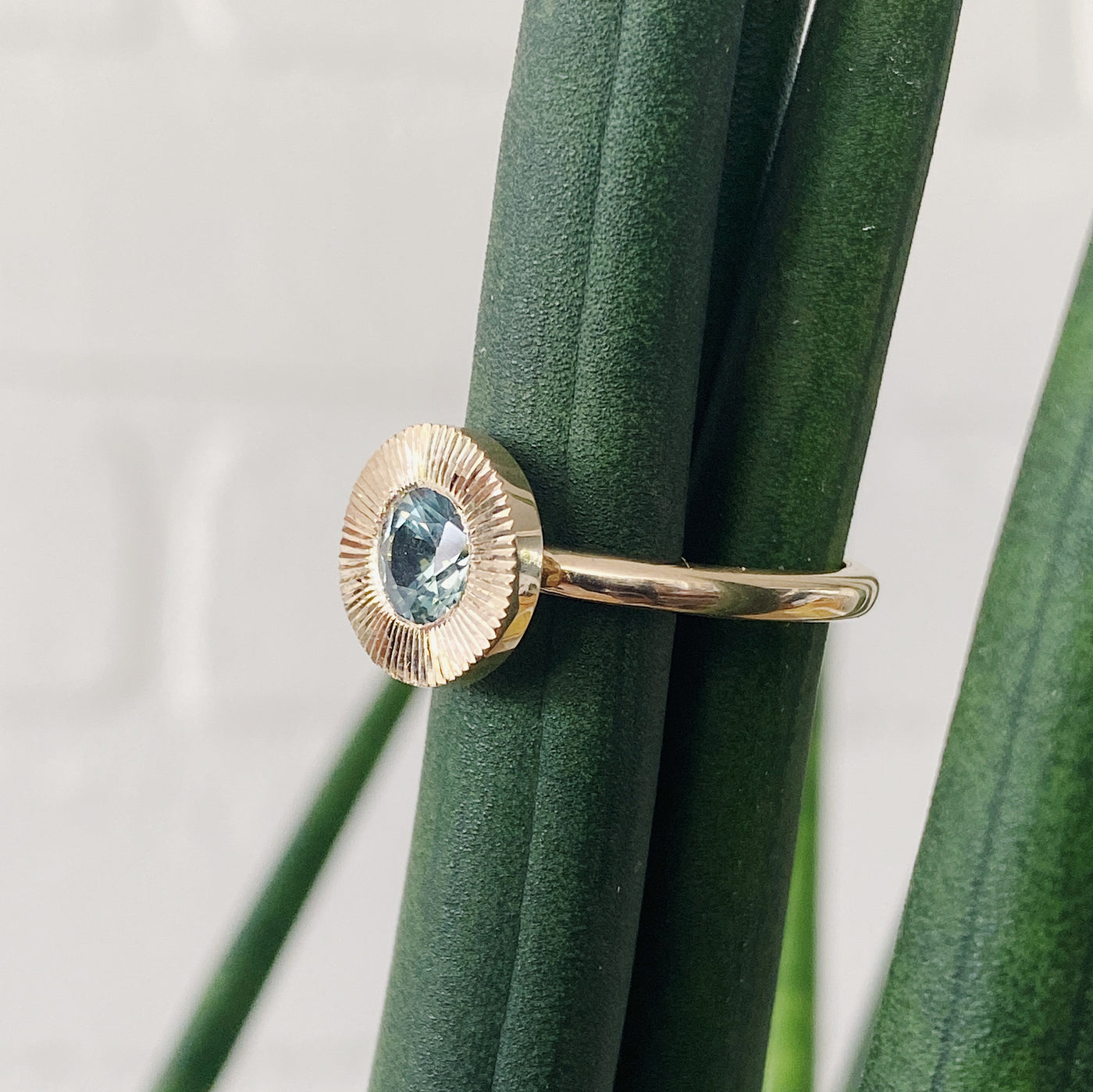 Side view of Round mint green Montana sapphire in a 14k yellow gold Aurora ring with an engraved halo border