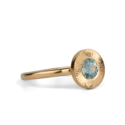 Other side view of Round mint green Montana sapphire in a 14k yellow gold Aurora ring with an engraved halo border on a white background