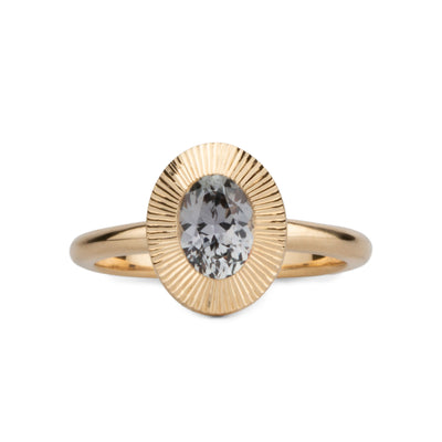 Oval grey-lavender Montana sapphire in a 14k yellow gold Aurora ring with an engraved halo border on a white background