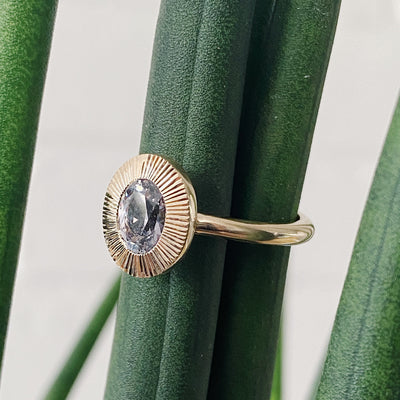 Oval grey-lavender Montana sapphire in a 14k yellow gold Aurora ring with an engraved halo border side view