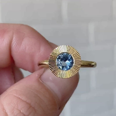 Round Medium Blue Montana sapphire in a 14k yellow gold Aurora ring with an engraved halo border. 