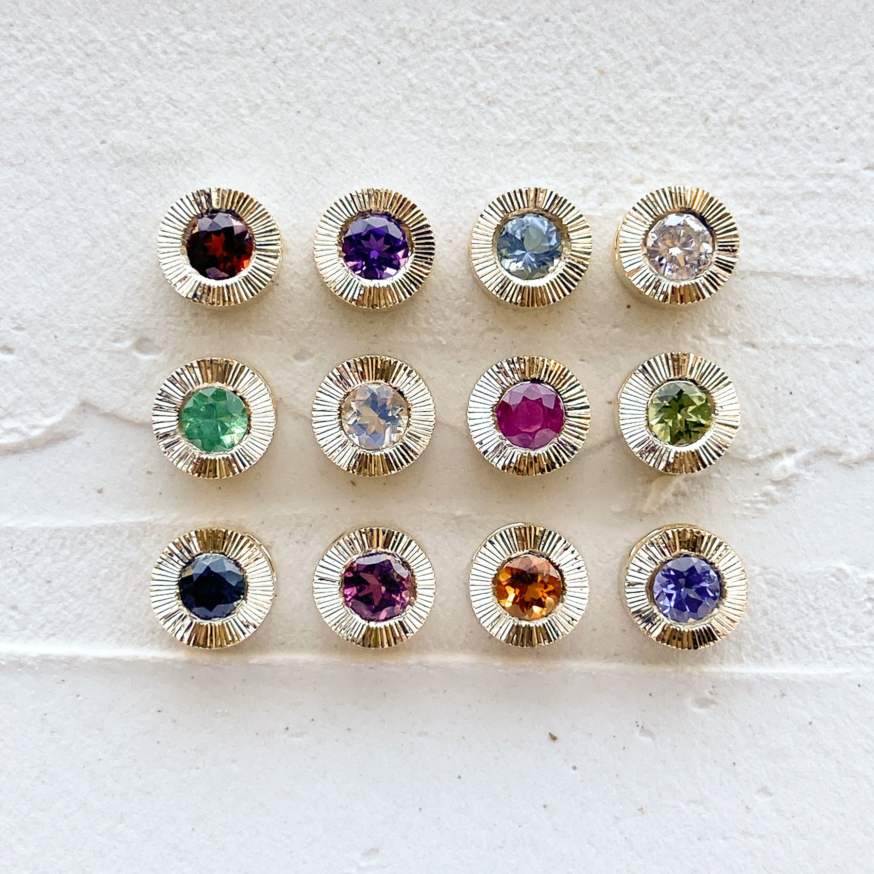 14k yellow gold aurora pendants with birthstones garnet for January,  amethyst for February, aquamarine for March, diamond for April, emerald for May, moonstone for June, ruby for July, peridot for August, blue sapphire for September, pink tourmaline for October, citrine for November, and tanzanite for December