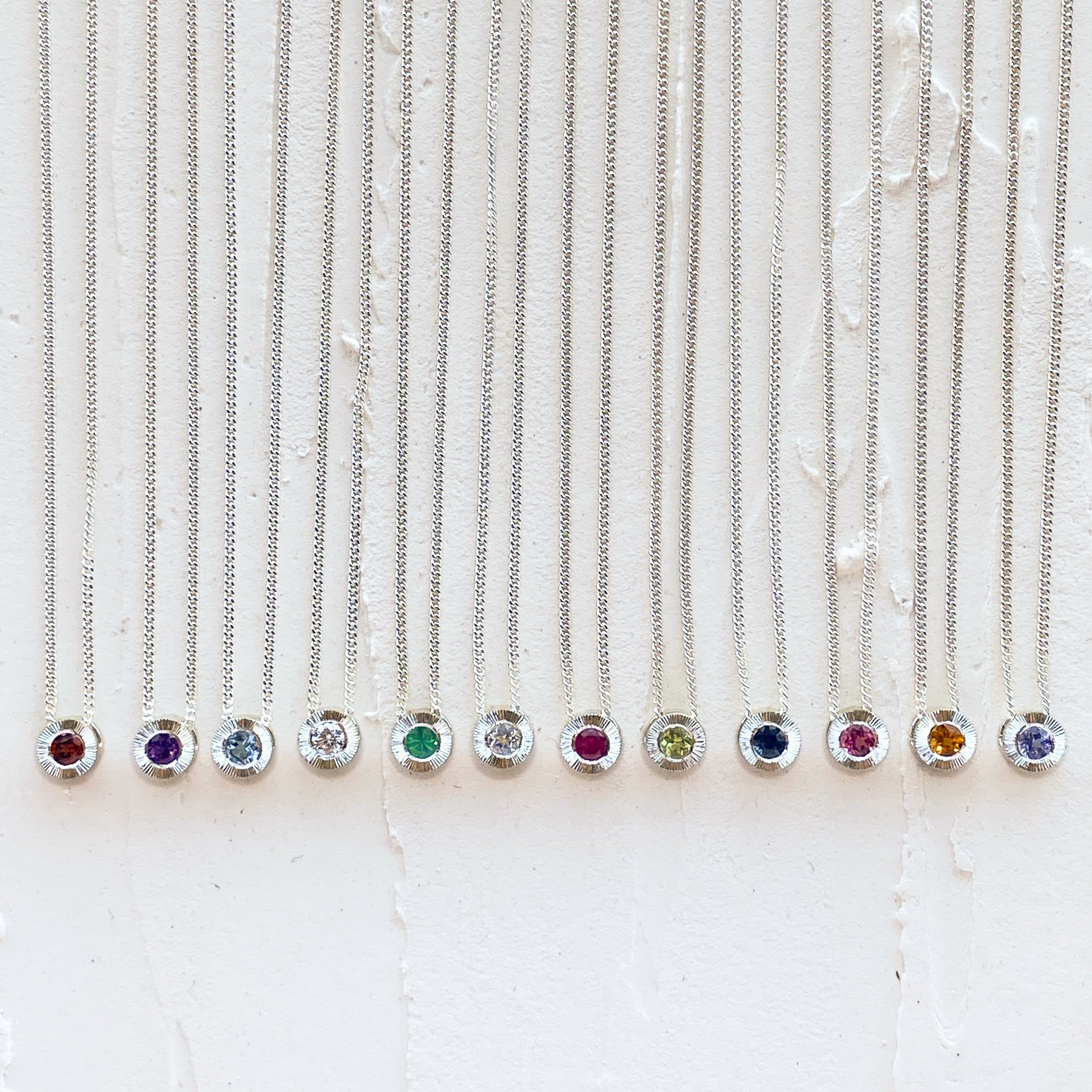 Sterling silver aurora necklaces with birthstones garnet for January,  amethyst for February, aquamarine for March, diamond for April, emerald for May, moonstone for June, ruby for July, peridot for August, blue sapphire for September, pink tourmaline for October, citrine for November, and tanzanite for December
