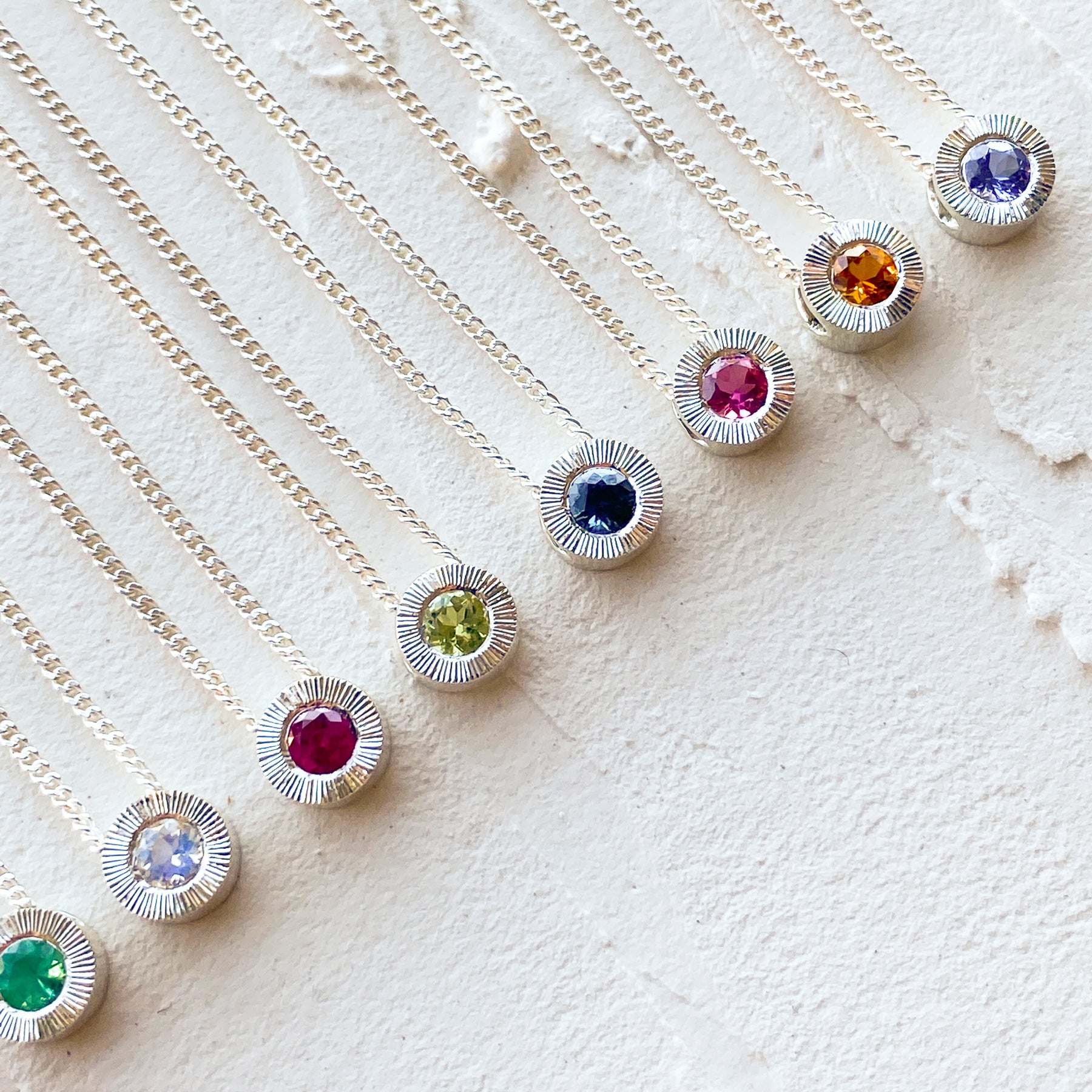 Sterling silver aurora necklaces with birthstones garnet for January,  amethyst for February, aquamarine for March, diamond for April, emerald for May, moonstone for June, ruby for July, peridot for August, blue sapphire for September, pink tourmaline for October, citrine for November, and tanzanite for December